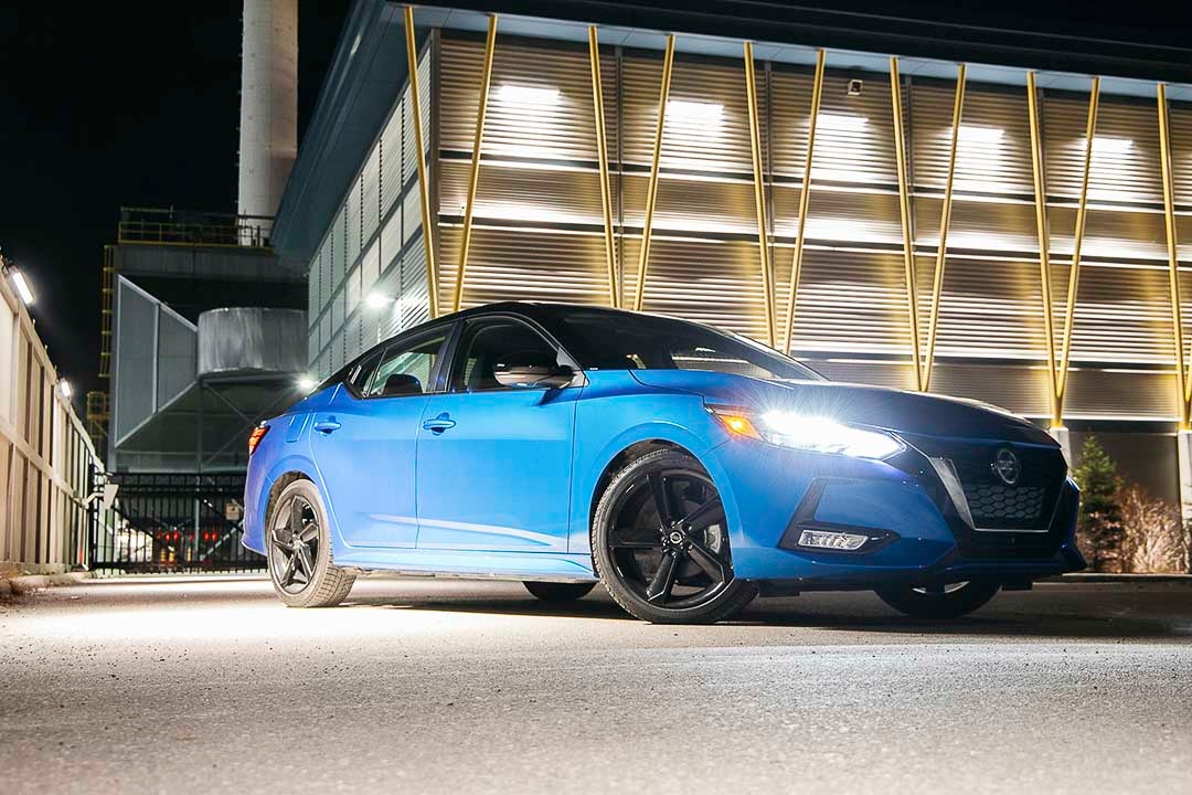 vue latérale avant de la Nissan Sentra 2021 stationnée devant un bâtiment le soir