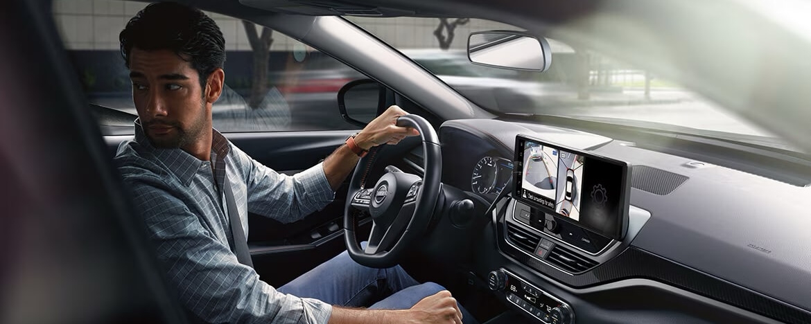 Homme au volant de la Nissan Altima 2025 utilisant l’assistance ProPILOT pour reculer.