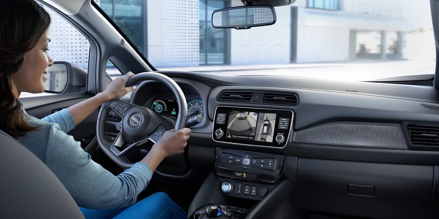 Femme au volant de la Nissan Leaf 2025 utilisant le système multimédia de pointe à bord de la voiture.